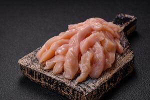 Raw chicken fillet cut into strips with spices and herbs photo