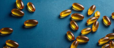 yellow fish oil omega 3 6 9 capsules soft gels on blue background top view with copy space. photo