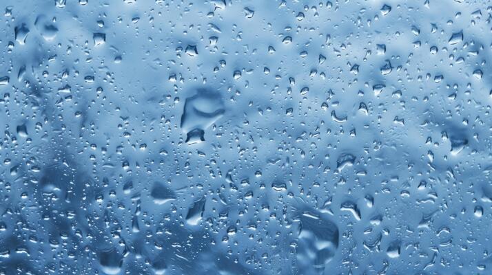 Upclose view of a stormy rain shower as each individual drop creates a unique ripple effect on the waters surface.