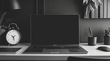 A monochromatic desk display featuring a sleek silver laptop matte black accessories and a simple white clock demonstrating the beauty of a minimalistic aesthetic photo