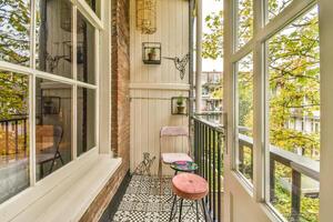 A balcony with a chair and a table in front of a window photo