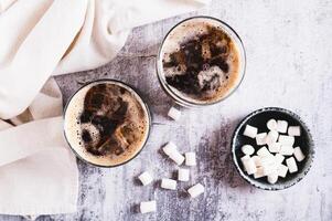Fusion drink of cola and marshmallow in glasses on the table top view photo