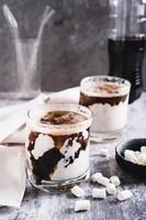 Fusion drink of cola and marshmallow in glasses on the table vertical view photo