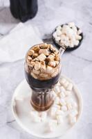 Refreshing fluffy coke with marshmallow in a glass on the table vertical view photo
