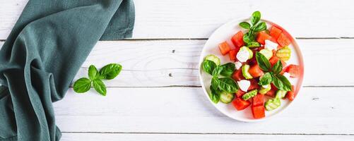 Diet mix of watermelon, cucumber, ricotta and basil on a plate top view web banner photo