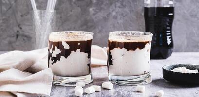 Fusion drink of cola and marshmallow in glasses on the table web banner photo
