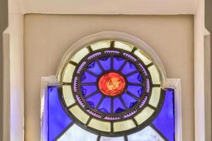 A stained glass window with a red sun in the center photo