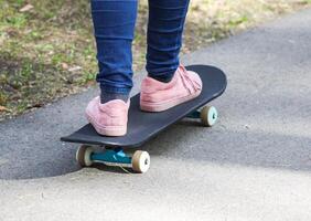 Child's legs on skateboard on asphalt road in park. photo