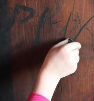 Child's hand drawing with coal on the wood photo