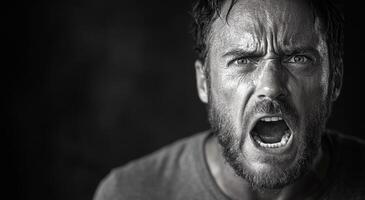 A man with a beard and a mouth open in a black and white photo. The man's expression is angry and he is yelling photo