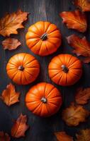 Four orange pumpkins are arranged on a wooden surface with some orange leaves. The arrangement creates a warm and inviting atmosphere, evoking the feeling of fall and harvest season photo