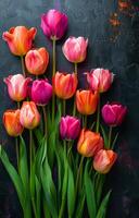 A bouquet of flowers with pink and orange petals. The flowers are arranged in a row and are placed on a black background. The arrangement gives off a warm and inviting feeling photo
