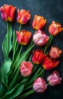 A bouquet of flowers with pink and orange petals. The flowers are arranged in a row and are placed on a black background. The arrangement gives off a warm and inviting feeling photo