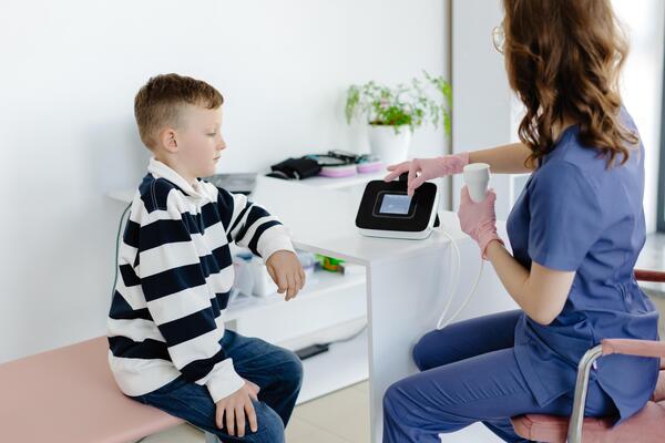 Boy testing breathing function by spirometry in doctors office. Diagnosis of respiratory function in pulmonary disease