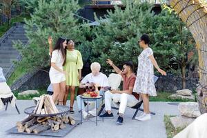 Multiracial group of friends is playing guitar, singing songs at dinner party in summer picnic photo