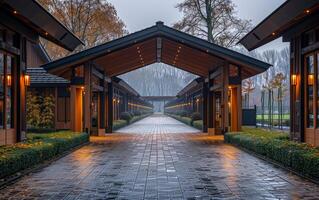 A long walkway with a roof over it. The walkway is wet and the lights are on photo