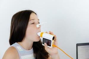 Girl testing breathing function by spirometry in doctors office. Diagnosis of respiratory function in pulmonary disease photo