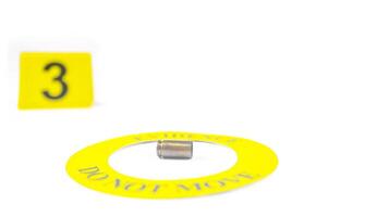 A spent bullet casing placed within a yellow circle, labeled with the text Evidence, Do Not Move, with a blurred number 3 tag, set against a white background, concept of crime investigation. photo