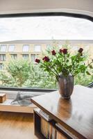 A vase of roses sitting on a table in front of a window photo