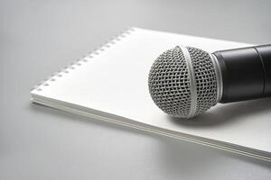 Close-up of microphone on notebook. a perfect setup for podcasting, interviews, and creative audio projects. Podcast record. Grey monochrome. Audiobook technology. Home school teaching. Edit episode photo