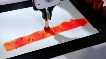 Robotic arm applying red paint to a white surface showcases smooth movements in a series of slow-motion shots video