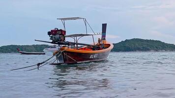 PHUKET, THAILAND - NOVEMBER 15, 2018 A long tail Asia boat is floating on small waves in Rawai Beach with islands and ship in background. video