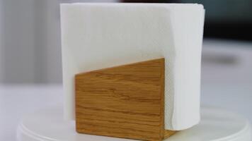 Wooden napkin holder with paper serviettes rotate on kitchen table. Space for text video