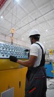 Black worker entering data in CNC machine at pvc window factory to get the production going. Vertical video
