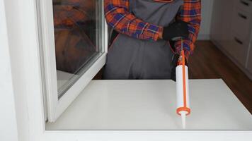 A worker is applying polyurethane foam to fill gap between sash and window frame video