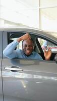 Happy african american man showing the key of his new car. Vertical video