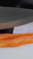 cortar vermelho peixe para Sushi mão cortar vermelho salgado peixe para dentro pedaços enquanto culinária, cozinhando sanduíches usando vermelho salmão peixe. homem corte vermelho peixe em de madeira borda. video