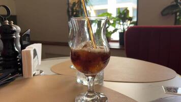 add ice to cola pour cola over ice cubes in glass on walnut table with space for text video