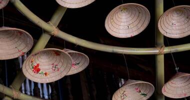 Collection of colorful Vietnamese hats on a sunny beach, developing in the wind. On the wall there is a decoration with Vietnamese hats, many different small and large headdresses video