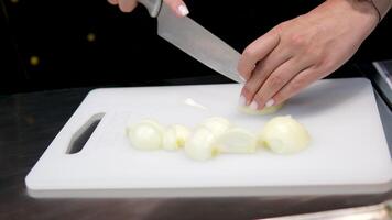 Close-up. cut onions Chef chopping an onion with fine pressure on a cutting surface in professional kitchen video
