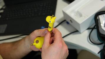 A pediatrician in a hospital checks the ear for children in the form of a giraffe in the hands of a doctor against the background of a table and a computer video