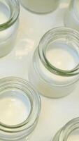 yogurt in glass jars, milk, and cream. Milk is poured into a glass and a jar using a spoon. Another glass of milk is also there video