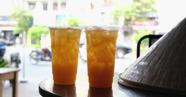 two plastic cups on table in asia vietnamese hat passing motorcycles in background travel drink orange and tangerine juice with ice video