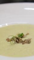 Close up view Spoon scoops up broccoli soup with sesame seeds on the surface. cream soup with seeds Delicious homemade creamy pumpkin soup with cream with sesame seeds and watercress. video