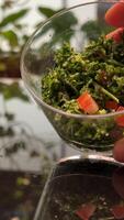 salad with greens and tomatoes, portioned Fresh salad with lettuce leaves and tomato falling into bowl, served with healthy food ingredients on white table, slow motion video