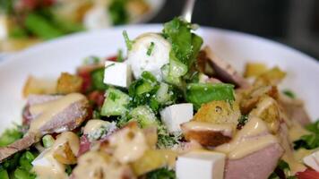 Eating Caesar salad with fork. Healthy salad made of chicken fillet, lettuce, tomatoes, quail eggs, croutons, parmesan cheese in a plate video