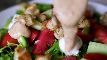 add sauce to salad. chef adds edible flowers to duck salad served on a deep white plate with dressing. video