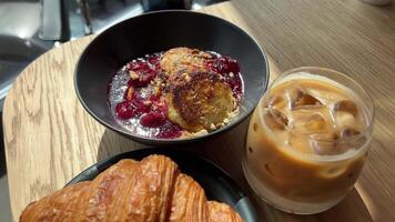 Ice latte croissant cottage cheese pancakes with cherry jam cut with a knife eat with a fork video