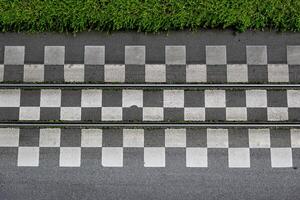 Directly above view of tram tracks running between rows of checkered tiles, bordered by greens photo