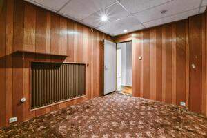 An empty room with wood paneling and a heater photo