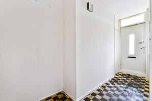 A hallway with a checkered floor and white walls photo