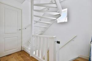 A white stairway in a small room with a door photo