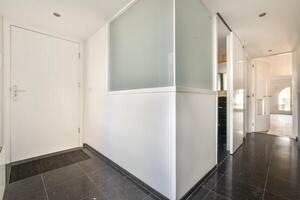 A hallway with white walls and black flooring photo