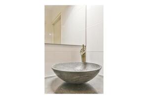 A bathroom sink with a stone bowl and a faucet photo