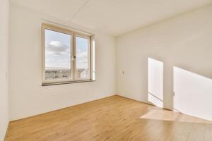 An empty room with a window and wooden floors photo