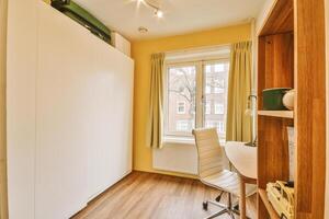 A small room with a desk and a window photo